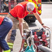 A fire cadet unreels a fire hose with the help of an instructor. Photo credit - Chris Bull.