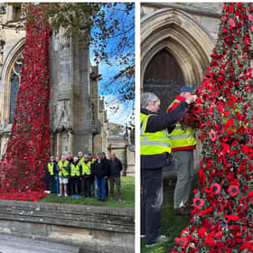 Volunteers proudly stand by their poppy cascade after wrestling it up onto St Denys' Church. Photo: Julie Butler
