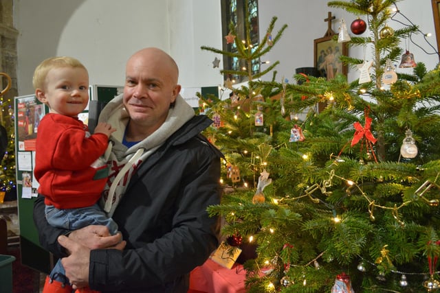 Adam Allenby and one-year-old Ashton with some of the decorated trees in the church