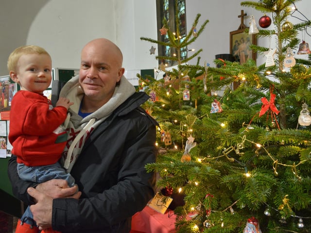 Adam Allenby and one-year-old Ashton with some of the decorated trees in the church