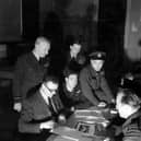 The debriefing following Operation CHASTISE. Squadron Leader Townson, the Intelligence Officer, questions, from left to right: Pilot Officers FM Spafford and HT Taerum and Flight Lieutenant RD Trevor-Roper, Sergeant J Pulford and Flight Sergeant GA Deering are partially hidden. Air Chief Marshal Air Arthur Harris and the Hon Ralph Cochrane, Air Officer Commanding 5 Group, observe.