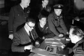 The debriefing following Operation CHASTISE. Squadron Leader Townson, the Intelligence Officer, questions, from left to right: Pilot Officers FM Spafford and HT Taerum and Flight Lieutenant RD Trevor-Roper, Sergeant J Pulford and Flight Sergeant GA Deering are partially hidden. Air Chief Marshal Air Arthur Harris and the Hon Ralph Cochrane, Air Officer Commanding 5 Group, observe.