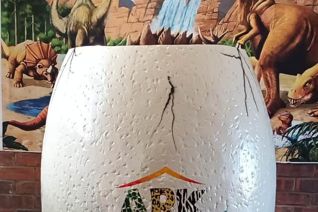 Pose for a photograph in a cracking dinosaur egg.