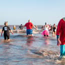 Braving the icy sea -- a waterlogged Malcolm Nix emerges from a previous 'Big Dip' as others make a splash. (PHOTO BY: Chris Frear Butterfield)