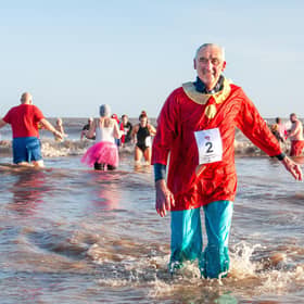 Braving the icy sea -- a waterlogged Malcolm Nix emerges from a previous 'Big Dip' as others make a splash. (PHOTO BY: Chris Frear Butterfield)