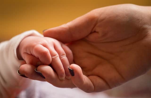 A mother holds the hand of a new baby.