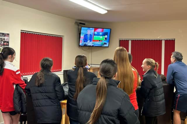The U15s girls watch theirs message on TV.