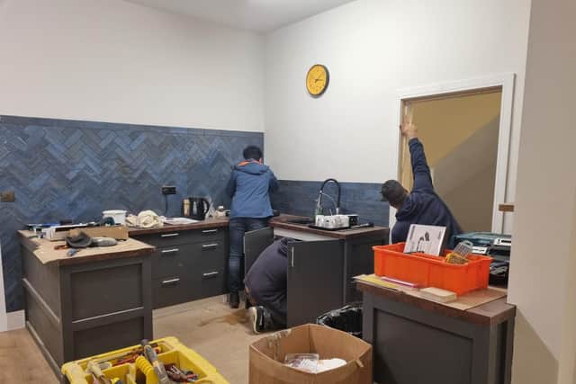 Asylum seekers putting finishing touches to the kitchen at the Storehouse Restore Centre.