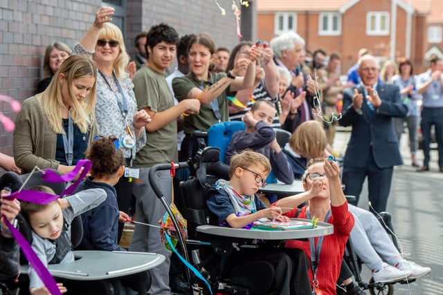 Parents, pupils and staff let off party poppers to celebrate the opening of their new school.