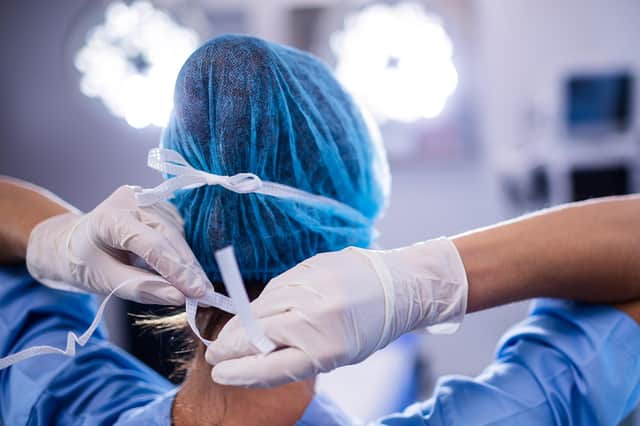Female nurse tying surgical mask in operation theatre at hospital