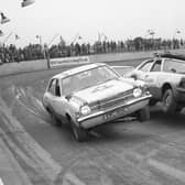 Two cars drive over a ramp at the same time, leaving them both on two wheels, at The Canadian National Auto Circus. This was one of the milder stunts performed for the crowd, with others involving fire.