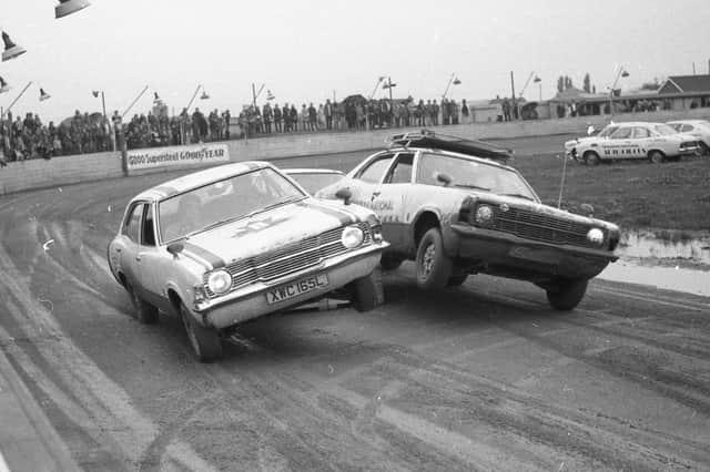 Two cars drive over a ramp at the same time, leaving them both on two wheels, at The Canadian National Auto Circus. This was one of the milder stunts performed for the crowd, with others involving fire.
