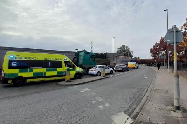 Two emergency vehicles, both with their flashing blue lights on, stuck in Boston town centre due to a goods train.