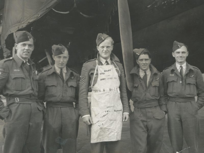 Geoffrey Appleyard and other crew members from the lost Avro Lancaster. The apron in the photo belonged to Kathleen Neal, whose family farmed near Benington. She had got to know Appleyard and several members of the crew through wartime dances at Boston's Assembly Rooms. After successful operations, she embroidered small bombs and target names onto the apron. Following the crash, she attended Geoffrey's funeral, where she met his family. Later, she would become godmother to Geoffrey's niece.
