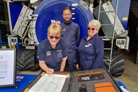 Mairi Perry, fundraising chairman, signs the RNLI 200 scroll at Skegness Lifeboat Station, watched by Coxwain Craig Willard and volunteer shop manager Chris Fisher.