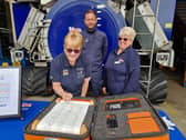Mairi Perry, fundraising chairman, signs the RNLI 200 scroll at Skegness Lifeboat Station, watched by Coxwain Craig Willard and volunteer shop manager Chris Fisher.