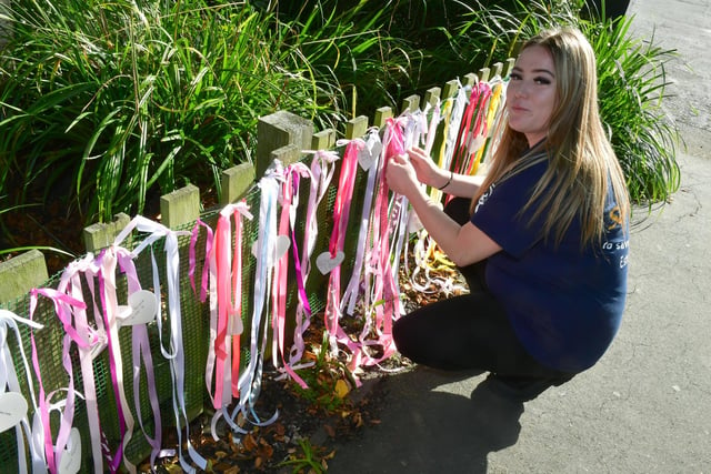 Kelsey Hiom tying ribbons to a fence in Boston's Central Park for Baby Loss Awareness Week.