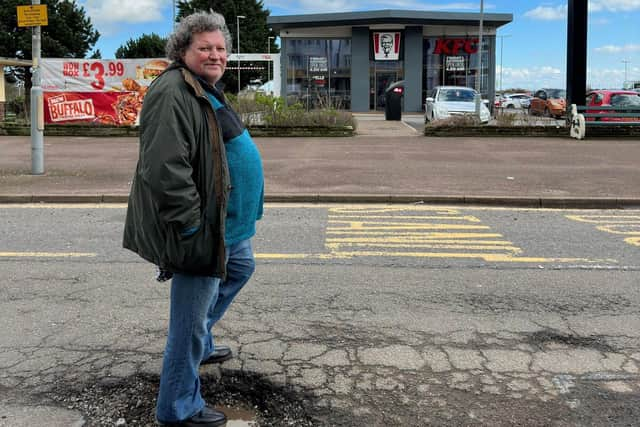 Resident Steve Wall standing in the pothole.