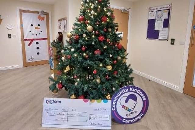 The large cheque from Platform Housing sits against the Christmas tree at Boston Women's Aid.