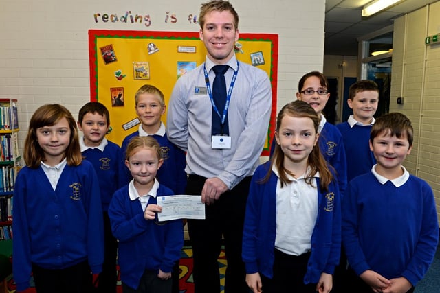 Lincolnshire Co-op presenting more than £200 to Tattershall Primary School, money raised through the organisation's Community Champions scheme. The school was planning to put the money towards the cost of new microphones that could be used in school performances. Pictured with pupils is Tattershall store manager Martin Ward.