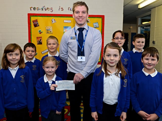 Lincolnshire Co-op presenting more than £200 to Tattershall Primary School, money raised through the organisation's Community Champions scheme. The school was planning to put the money towards the cost of new microphones that could be used in school performances. Pictured with pupils is Tattershall store manager Martin Ward.