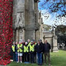 Volunteers proudly stand beside the installed poppy cascade at St Denys' Church. Photo: Julie Butler
