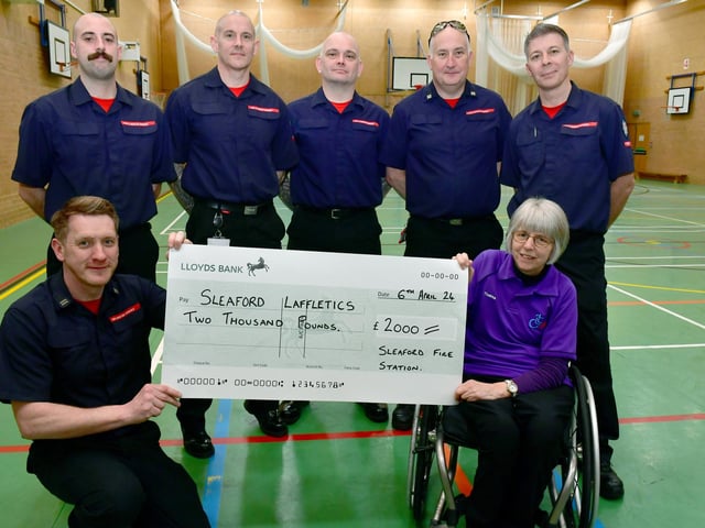 Firefighters L-R Colin Calam, George Benson, Stu Hill, John Wheat, Stu Annible and Bob Machin presenting a cheque to Thelma Smith. Photo: David Dawson