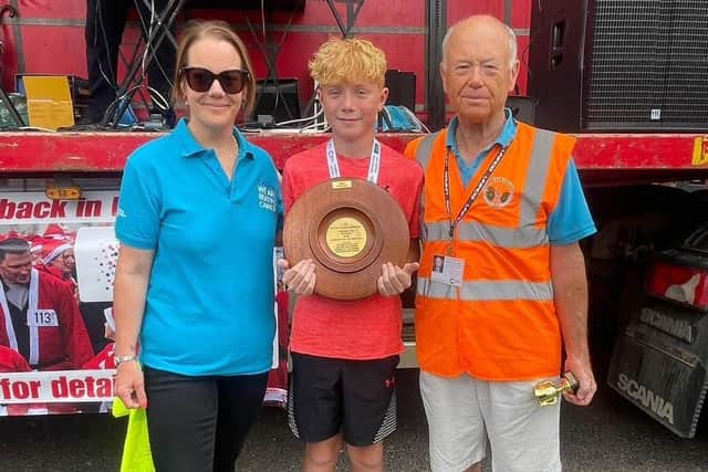 Harry Otty, the winner of the under-12s run for the second year on the trot, receives the Toni Cummings Memorial Trophy from Toni's husband, Gordon Cummings, and daughter, Kathryn Axton.