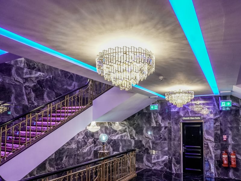 Traditional chandeliers hang over modern neon strip lights.