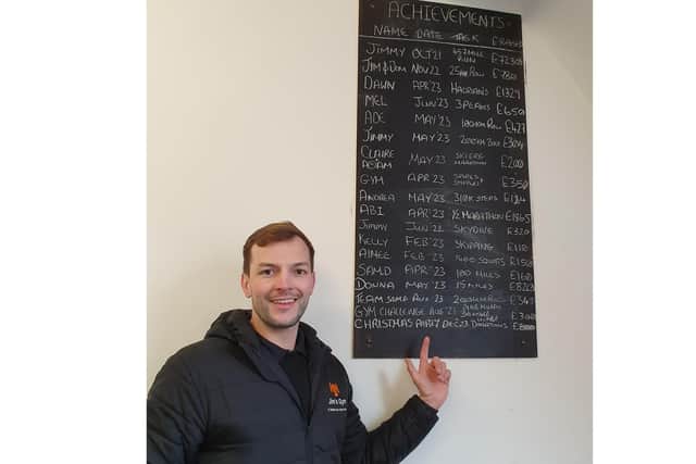 Jimmy Dexter with the achievements board for his gym members' fundraising efforts.