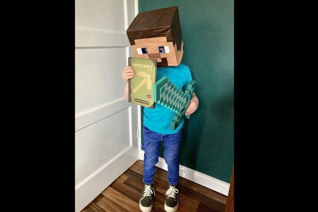 Finley Seymour, five, of Boston, as Steve from Minecraft, with one of his favourite books - Minecraft: Beginner's Handbook.