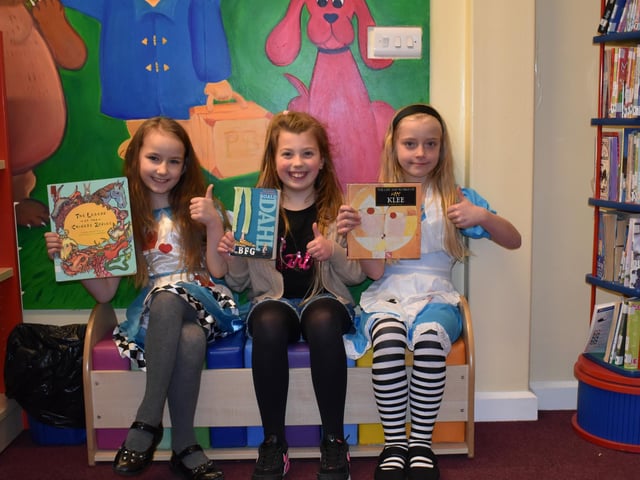 Three pupils enjoying a book at the school library.