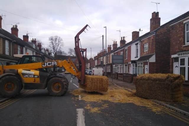 A JCB clears hay bales which fell from a tractor's trailer onto a road and pavement in Gainsborough earlier this year. Image: Lincolnshire Police.