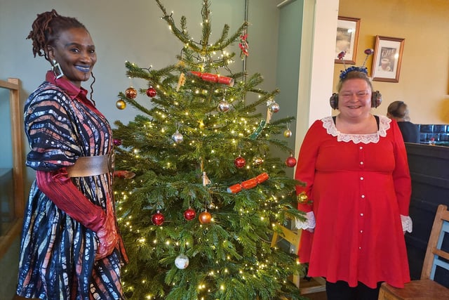 Hostess Bamidele Akomolafe (left) with volunteer Donna Carlton by the tree donated by Chapel St Leonards Garden Centre.