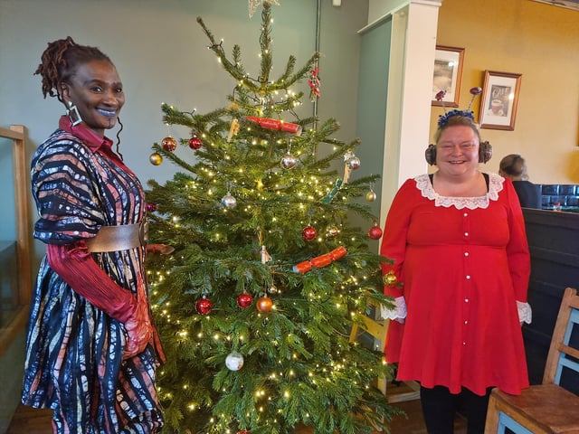 Hostess Bamidele Akomolafe (left) with volunteer Donna Carlton by the tree donated by Chapel St Leonards Garden Centre.