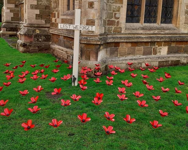The display of 101 poppies, made from recycled drink-cans, and a white cross in the grounds of St Mary's Church, Horncastle.