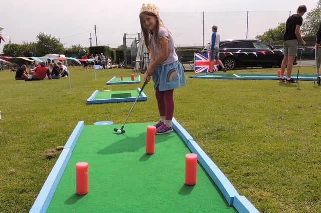Having a go at the crazy golf game during the jubilee sports and fair at Cranwell, six year old villager Eleanor.