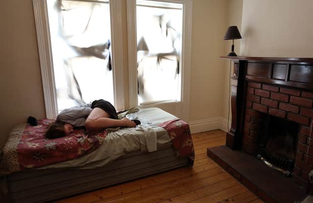 PICTURE POSED BY MODEL. A woman shelters looking scared on a bed.