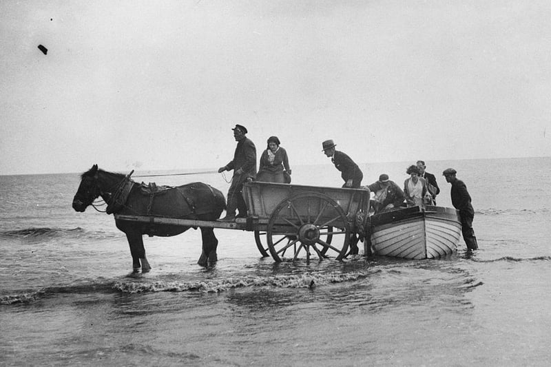 Visitors to Skegness scramble onto a cart which will transport them to the shore after their boat trip around the coastline, circa 1930.