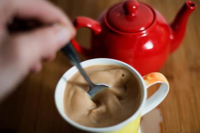 A cup of tea with milk is stirred.