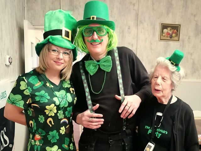 Team members Cheryl Curtis and Mark Haslam having a photo with Joyce Knight showing off her St Patrick's day top.