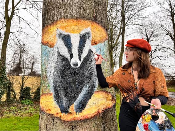 Mural artist Nikita Spires with her badger mural on Eastfield Road.