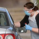 A worker in PPE including gloves, a face mask, eye protection and an apron, swabs an NHS worker at a drive-in facility to set up to test for the novel coronavirus COVID-19, in the car park of Chessington World of Adventures (Photo: BEN STANSALL/AFP via Getty Images)