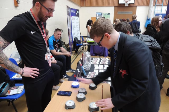 Axel Sedgwick, Student Enrichment Coordinator at Boston College, looks on as Harry Green, 15, of St George's Academy tests out his reaction speed on the light buttons.