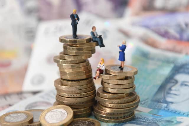 Models of men and women on a pile of coins and bank notes.