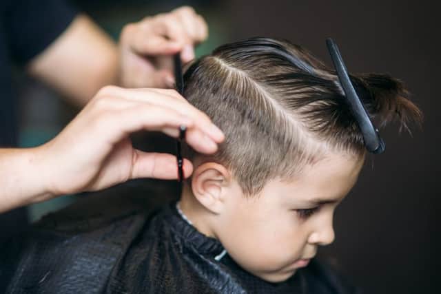 Little boy on a haircut in the barber sits on a chair.
