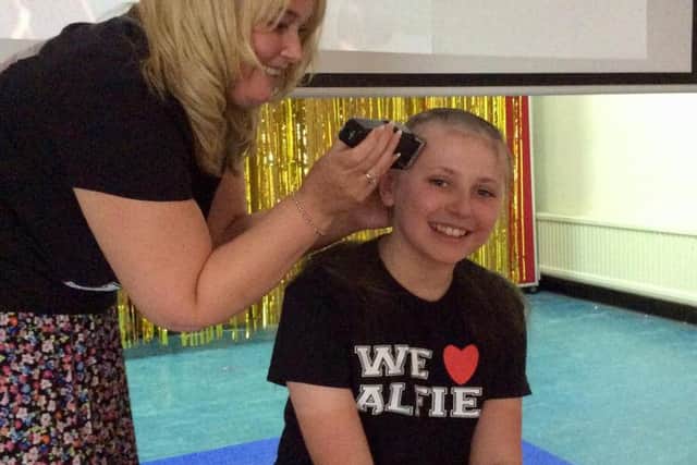 Zac Dickinson has his head shaved by headteacher Katie Barry.