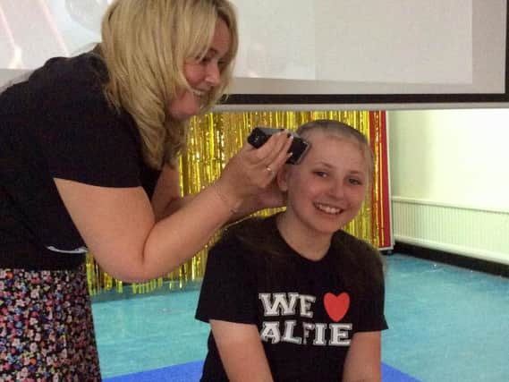 Zac Dickinson has his head shaved by headteacher Katie Barry.