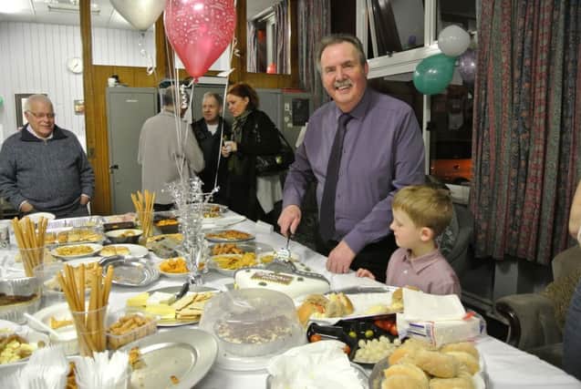 Alan Whyles cuts his retirement cake with help from seven-year-old grandson Owen