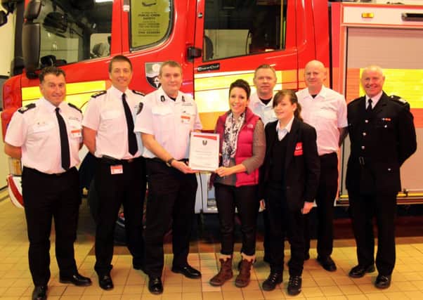Bravery award for Catherine Neary who pulled a man from his burning car after a crash. Catherine is pictured with her daughter Agatha and South Yorkshire Fire and Rescue staff at Maltby fire station.